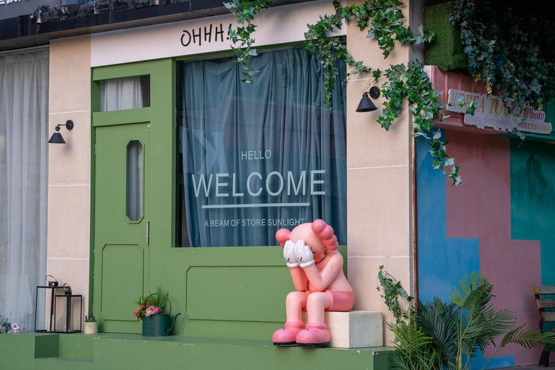 KAWS companion in front of a photo shop (slogan: "A beam of store sunlight") in Yangjing, Shanghai. Life-size sculptures and other iconography of the Companion are ubiquitous here; there is a mural on the same block, and a standing Companion sculpture in an alley a block away.